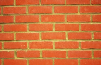 A uniform pattern of red bricks arranged in horizontal rows with pale yellow mortar in between.
