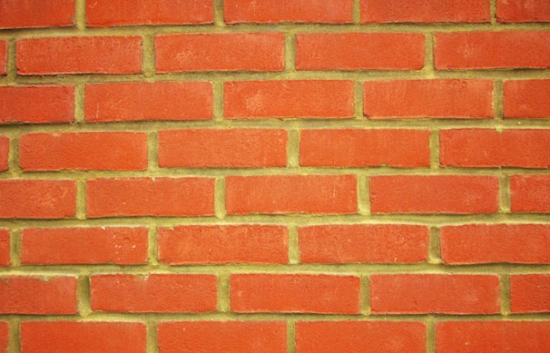 A uniform pattern of red bricks arranged in horizontal rows with pale yellow mortar in between.
