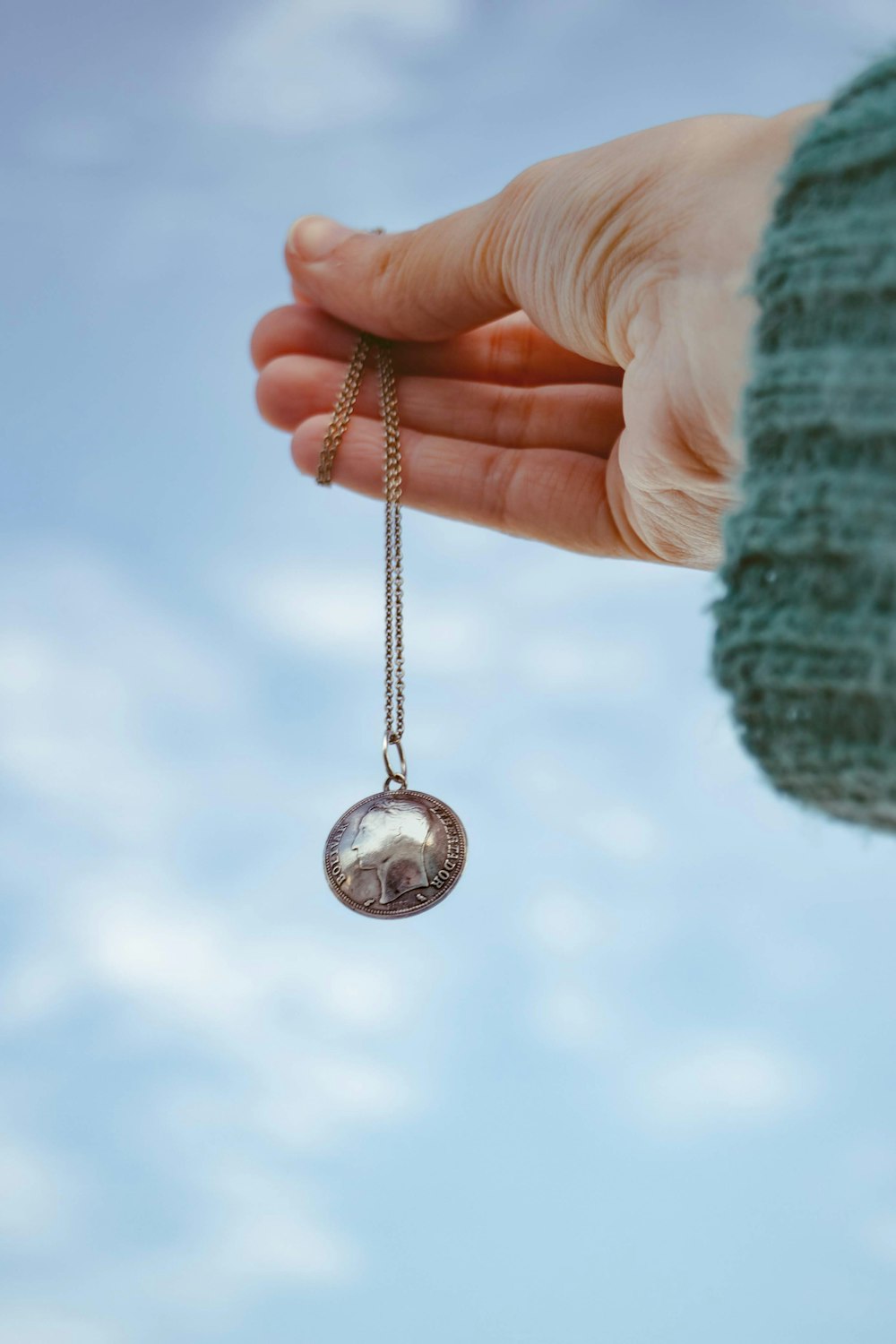 silver round pendant on persons hand