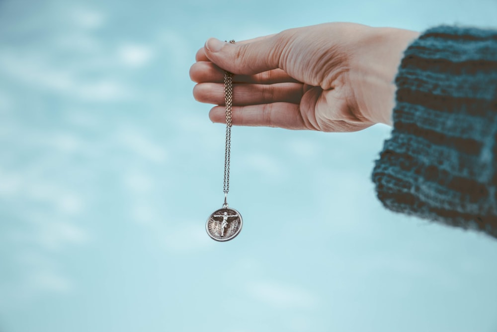 person holding silver round pendant