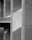 A close-up view of a textured concrete architectural structure, featuring large columns and a geometrical play of light and shadows across the surface.