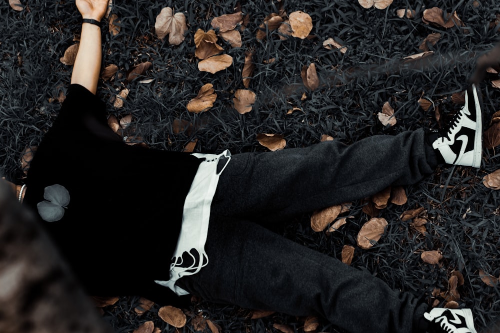 person in black pants standing on dried leaves