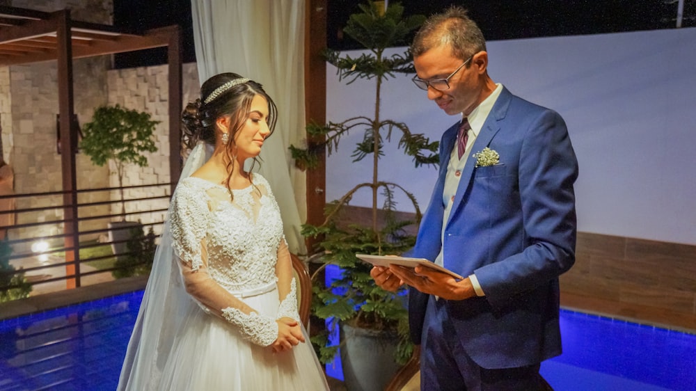 man in blue suit jacket holding woman in white dress