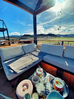 An inviting outdoor daybed draped with light throws under a shady pergola.