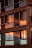 Modern residential building facade with large glass windows at sunset.