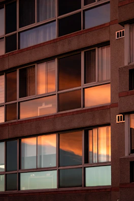 Modern residential building facade with large glass windows at sunset.