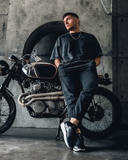 Model leaning on a vintage motorcycle wearing a rawvolt tee, capturing a rebellious street style