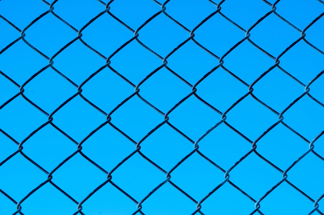 Chain link fence mesh against bright blue sky