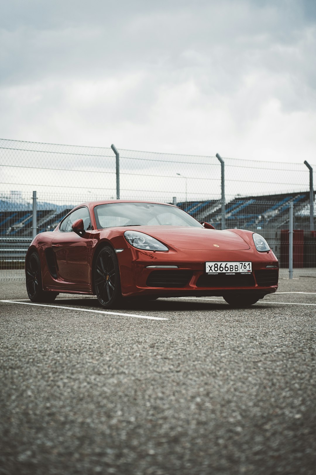 red porsche 911 parked near gray metal fence during daytime