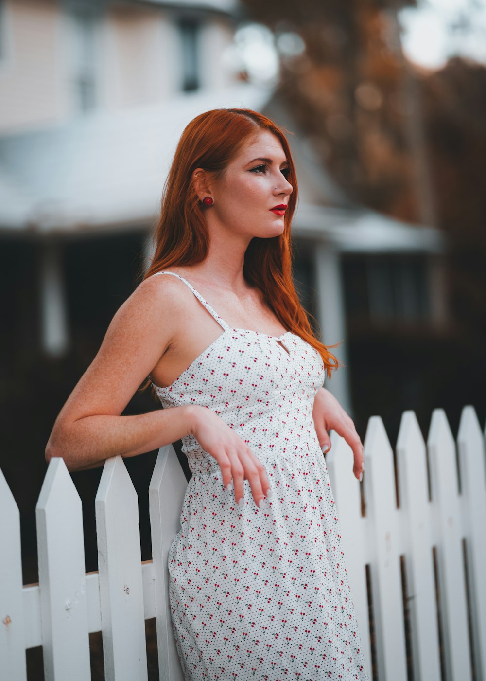 a woman leaning on a white picket fence