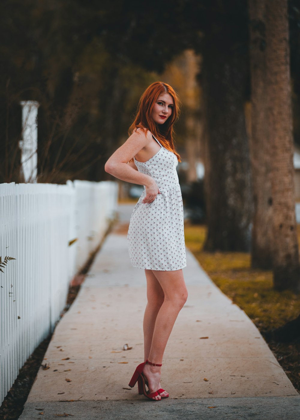 a woman in a white dress standing on a sidewalk