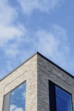 Construction workers laying bricks on a modern residential building under clear skies.