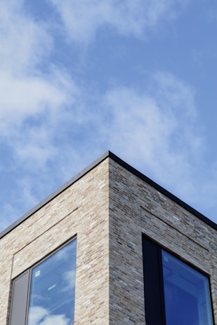 Construction workers laying bricks on a modern residential building under a clear blue sky.