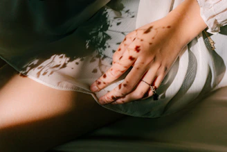 Close-up of a model's hand delicately holding a silk scarf with intricate patterns, bathed in soft natural light.