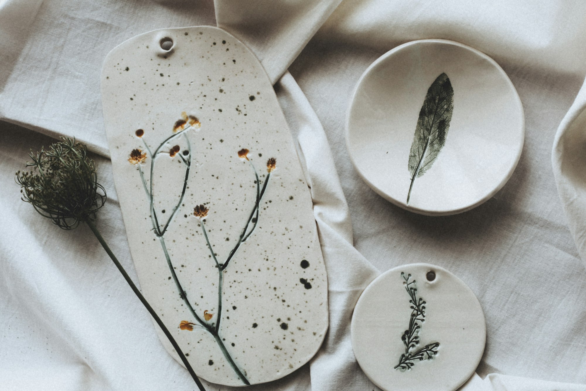 Handmade pressed-flower ceramics on soft linen — ritual, calm, and intention