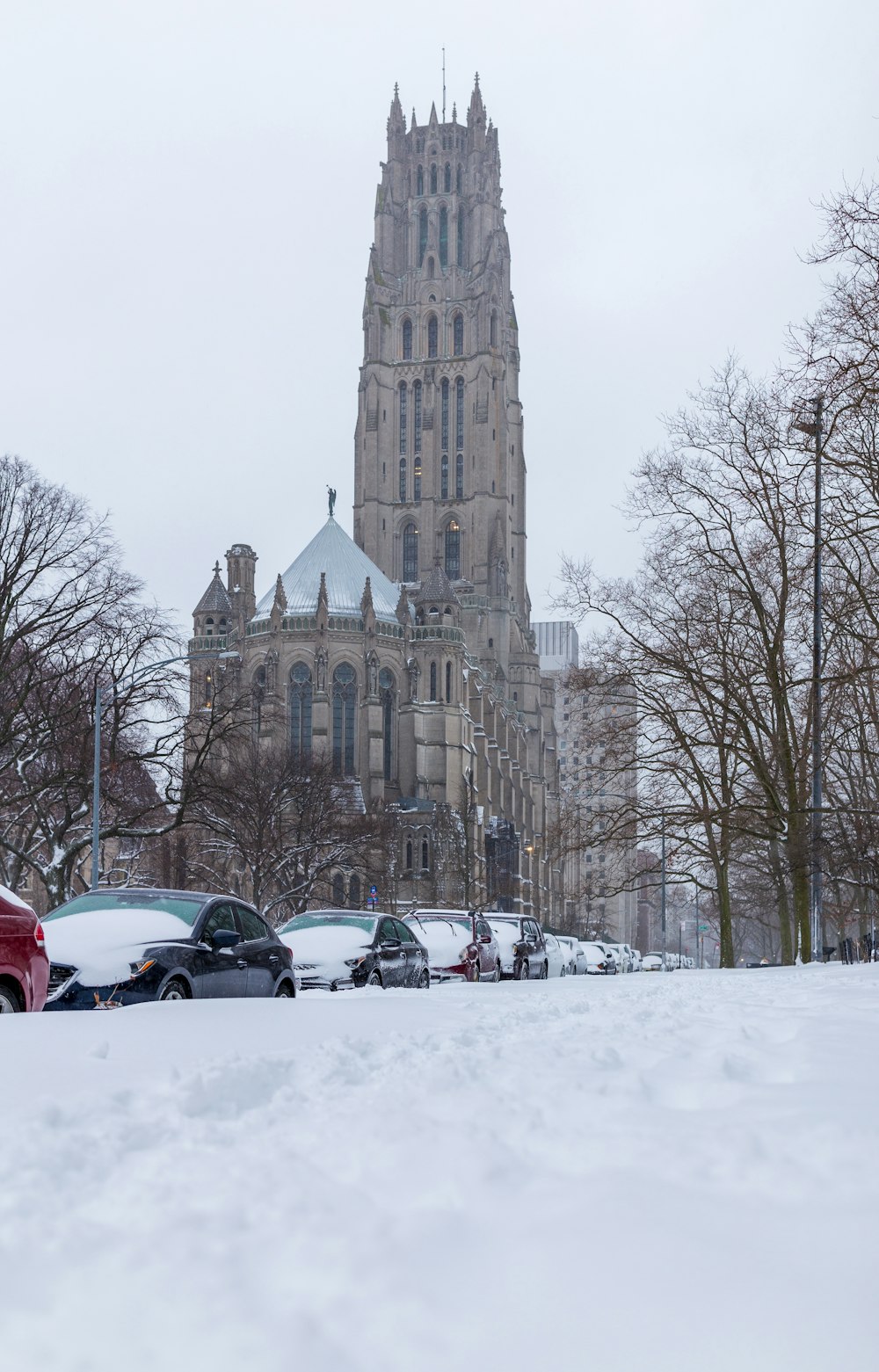 cars parked on snow covered road near brown concrete building during daytime