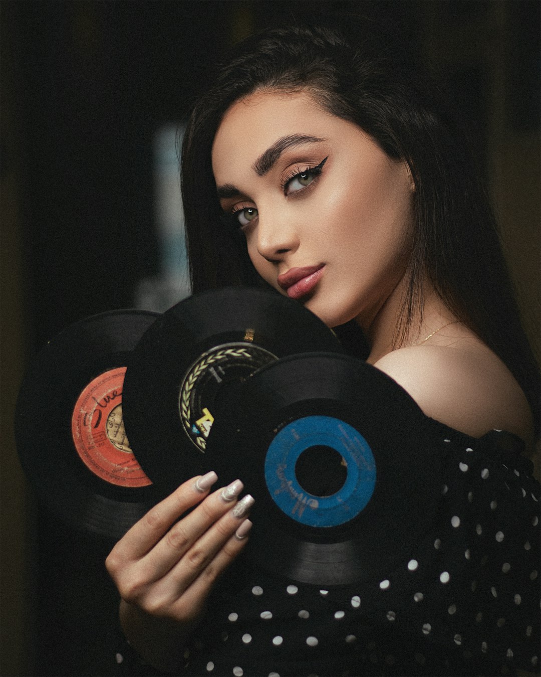 woman in black and white polka dot dress holding vinyl record