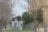 Large metallic letters displaying the acronym 'MNAC' are positioned near bare trees and a section of a classical building. The scene is set in an outdoor environment with a pathway leading alongside the building.
