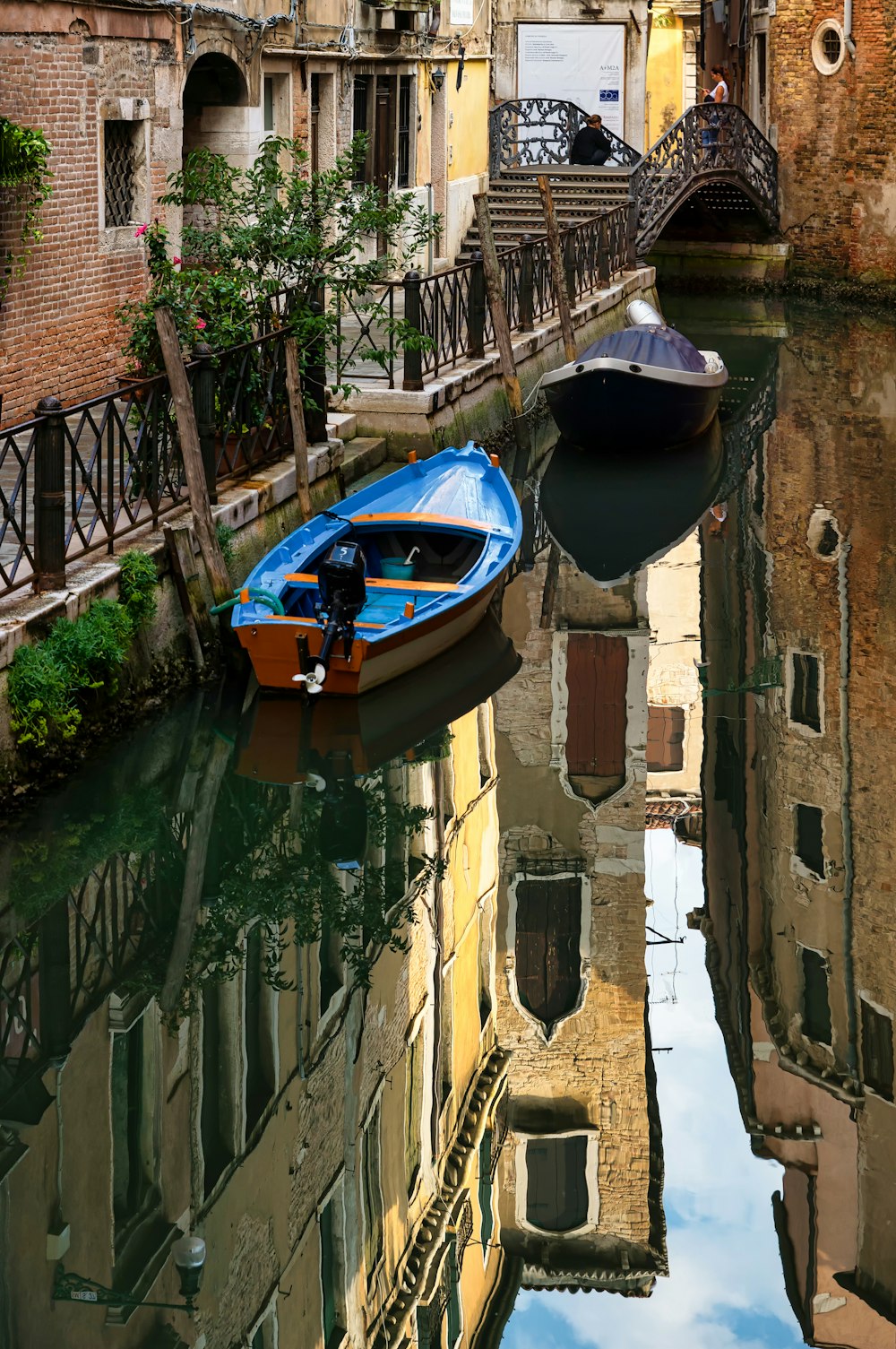 blue and black boat on river between brown concrete buildings during daytime