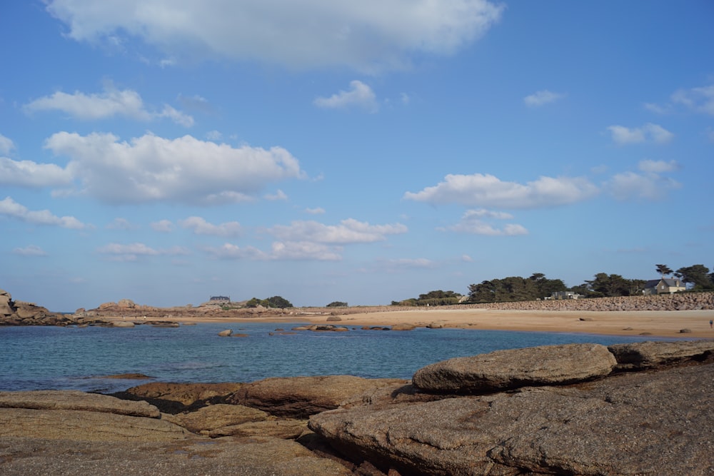 brown rocky shore under blue sky and white clouds during daytime