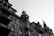 An architectural shot depicting a series of classic buildings with intricate design elements. The structures exhibit ornate balconies, detailed window frames, and a range of roof shapes. The image is captured in black and white, highlighting the textures and lines of the facades under a clear sky.