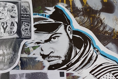 A stylized street art collage features a monochrome illustration of a man’s face wearing a hood. The artwork incorporates bold black and white lines with blue accents. To the left, a black and white print displaying cartoon characters overlaid on a TV screen adds a nostalgic element. A variety of textures and abstract backgrounds are present, contributing to a dynamic urban aesthetic.