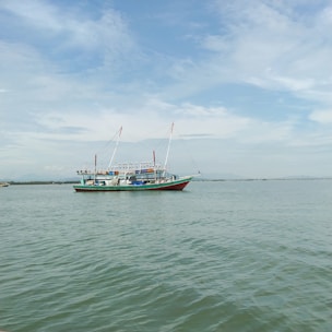 A sleek fishing vessel cruising through calm blue waters under a clear sky.