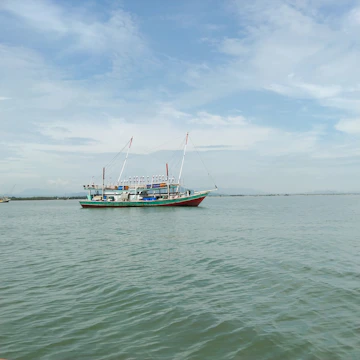 Fishing vessel equipped with satellite communication gear on calm waters at sunrise.