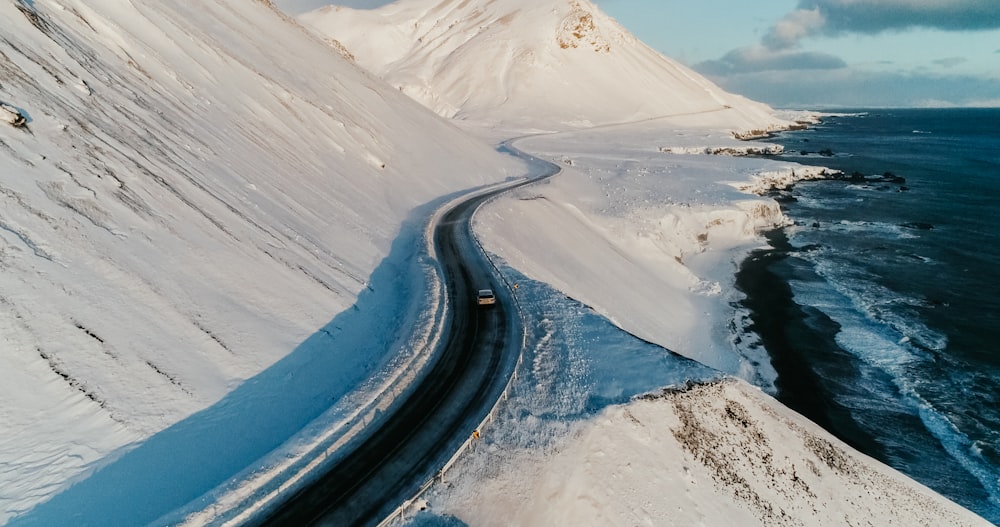 black asphalt road in between snow covered ground during daytime