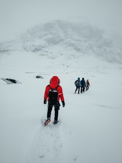 people in red jacket walking on snow covered ground during daytime