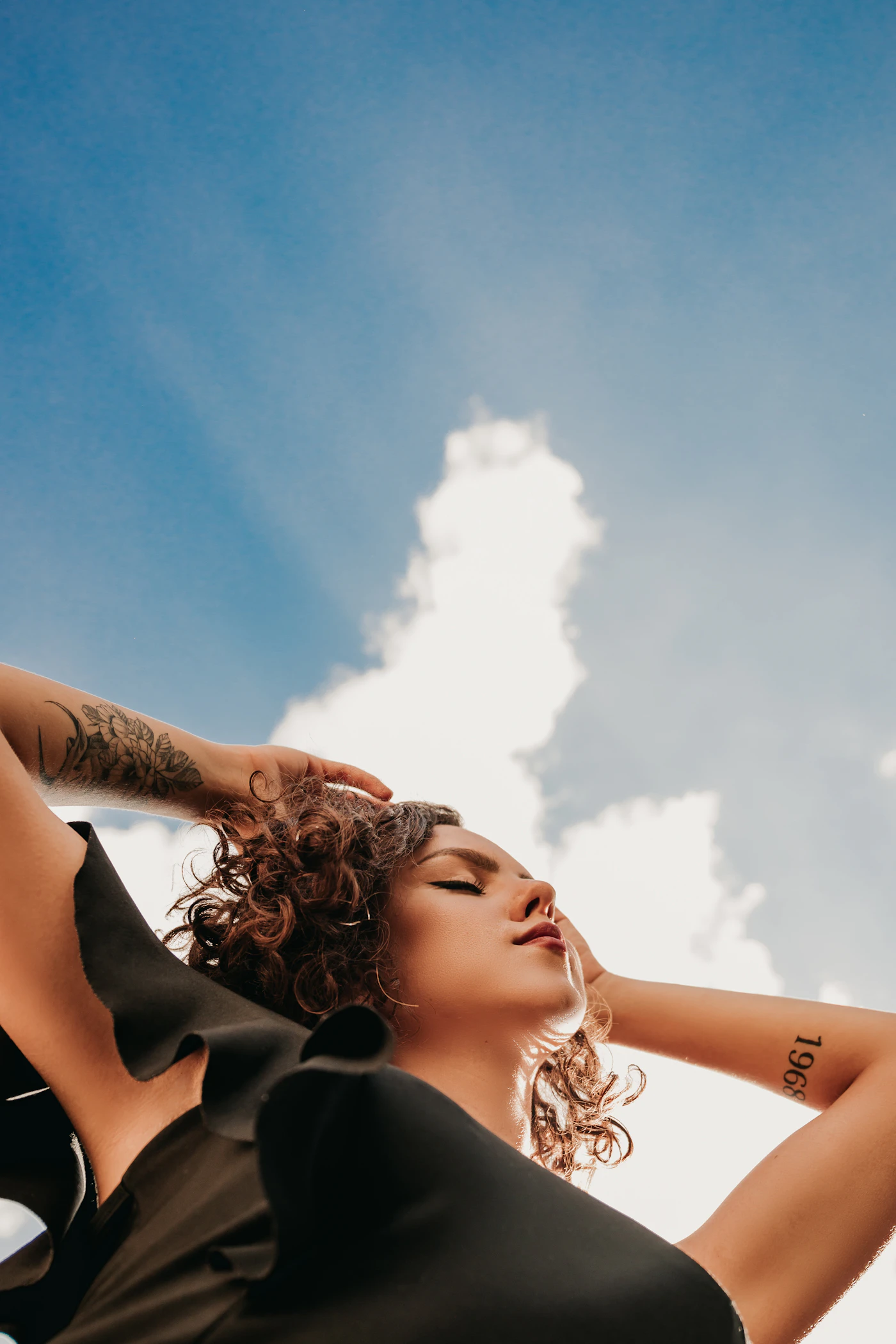 A woman lying back under a bright sky