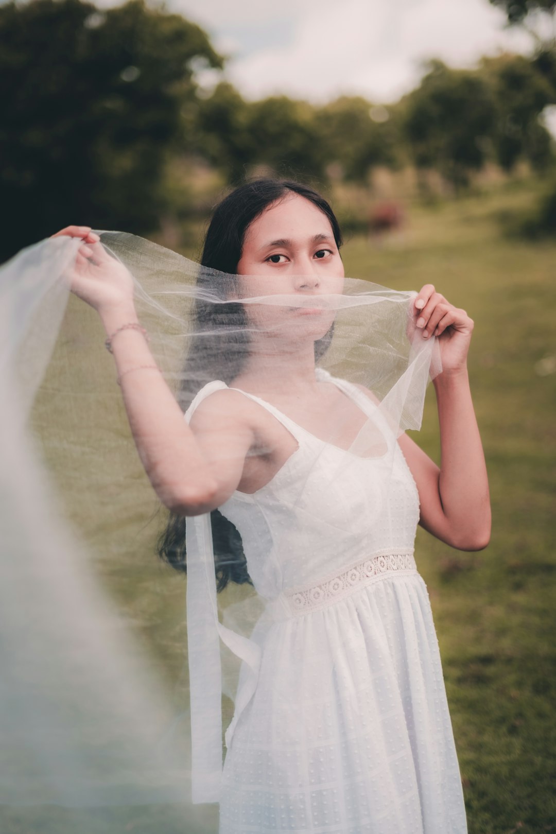 woman in white dress holding white sheer textile