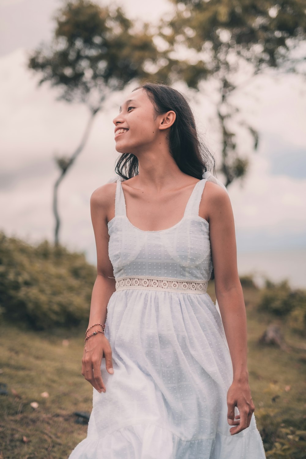 woman in white tank dress standing on green grass field during daytime