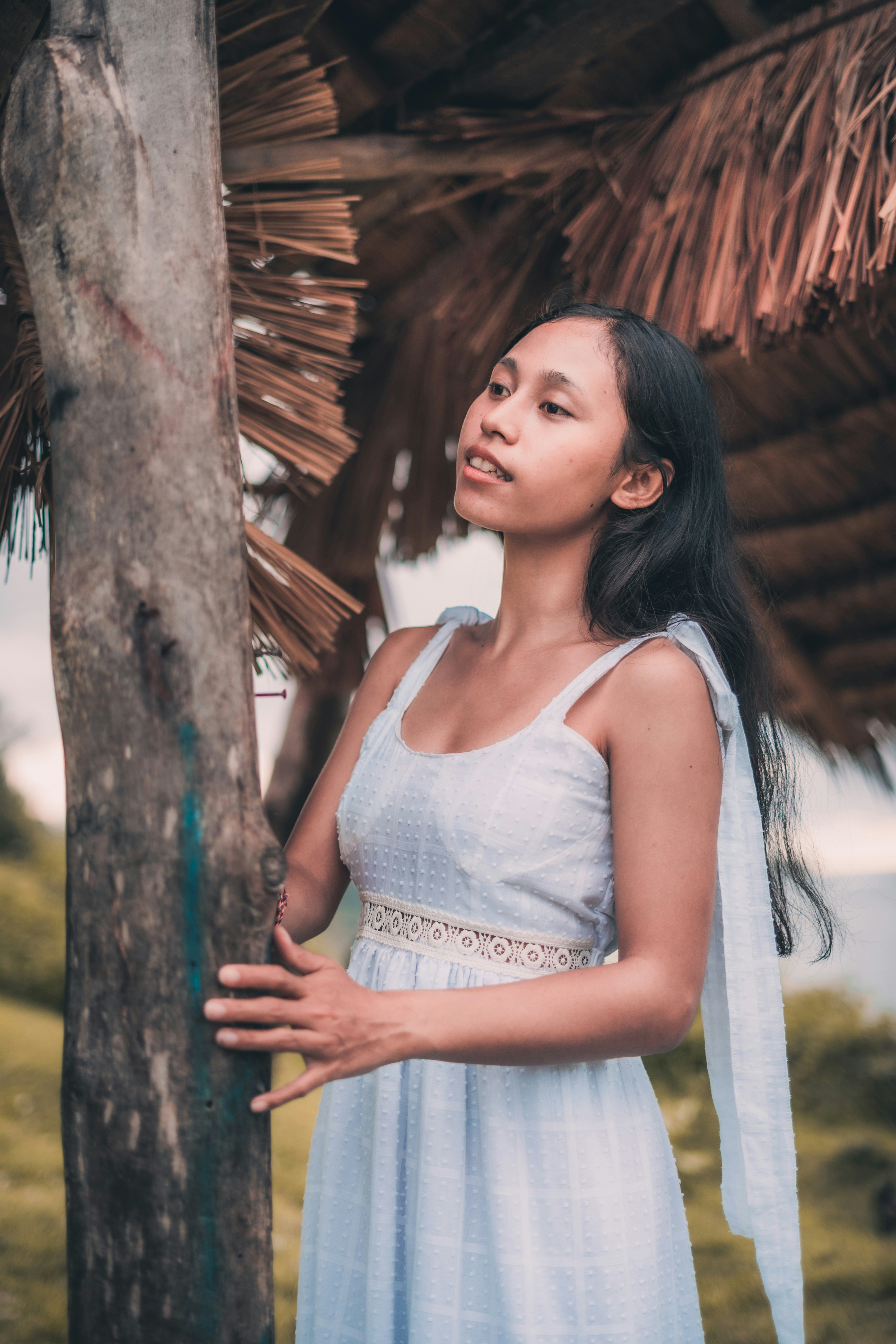 woman in white tank top standing beside brown tree