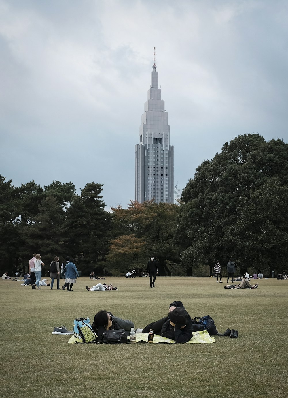 people sitting on green grass field near white high rise building during daytime