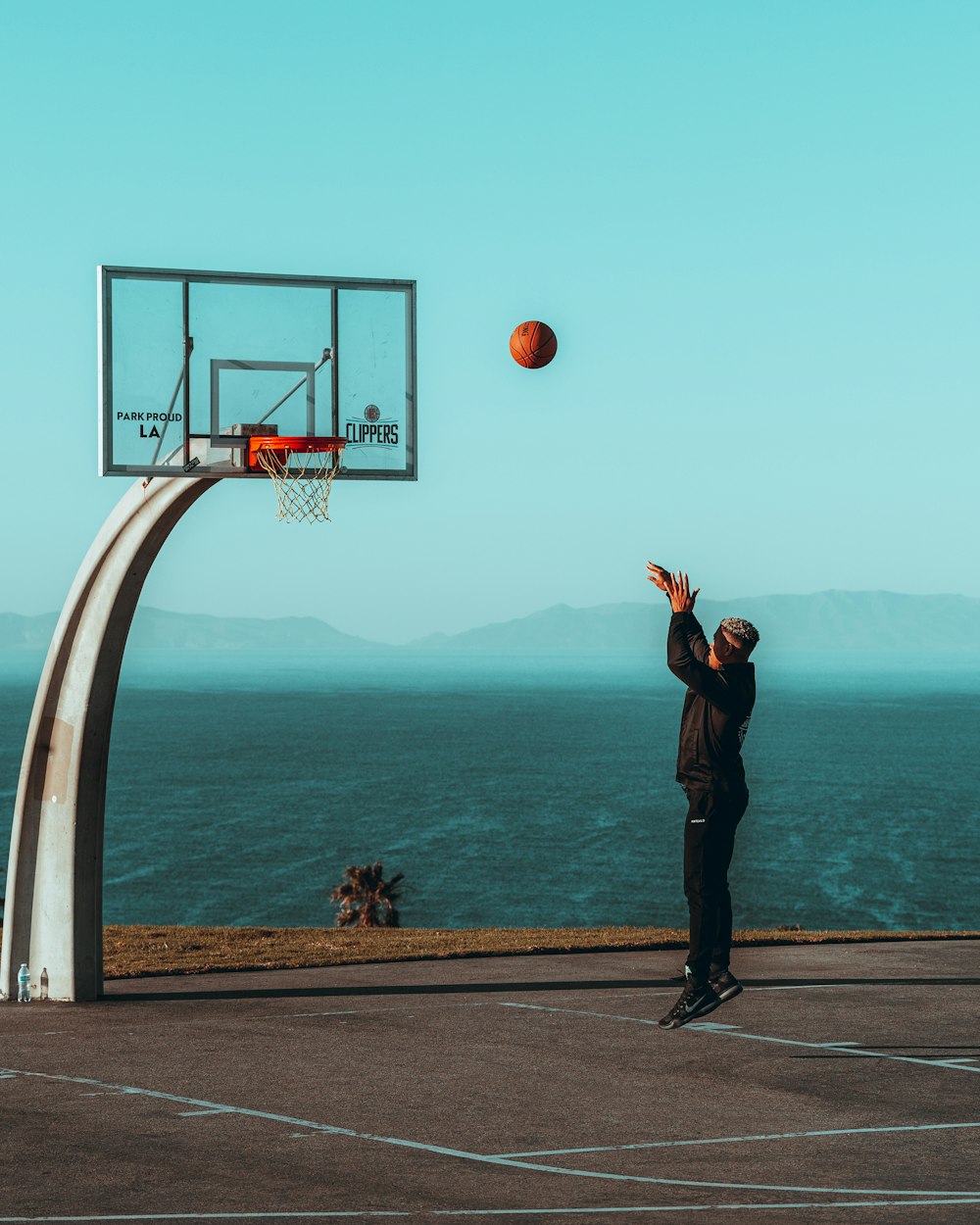 man in black jacket standing on basketball hoop