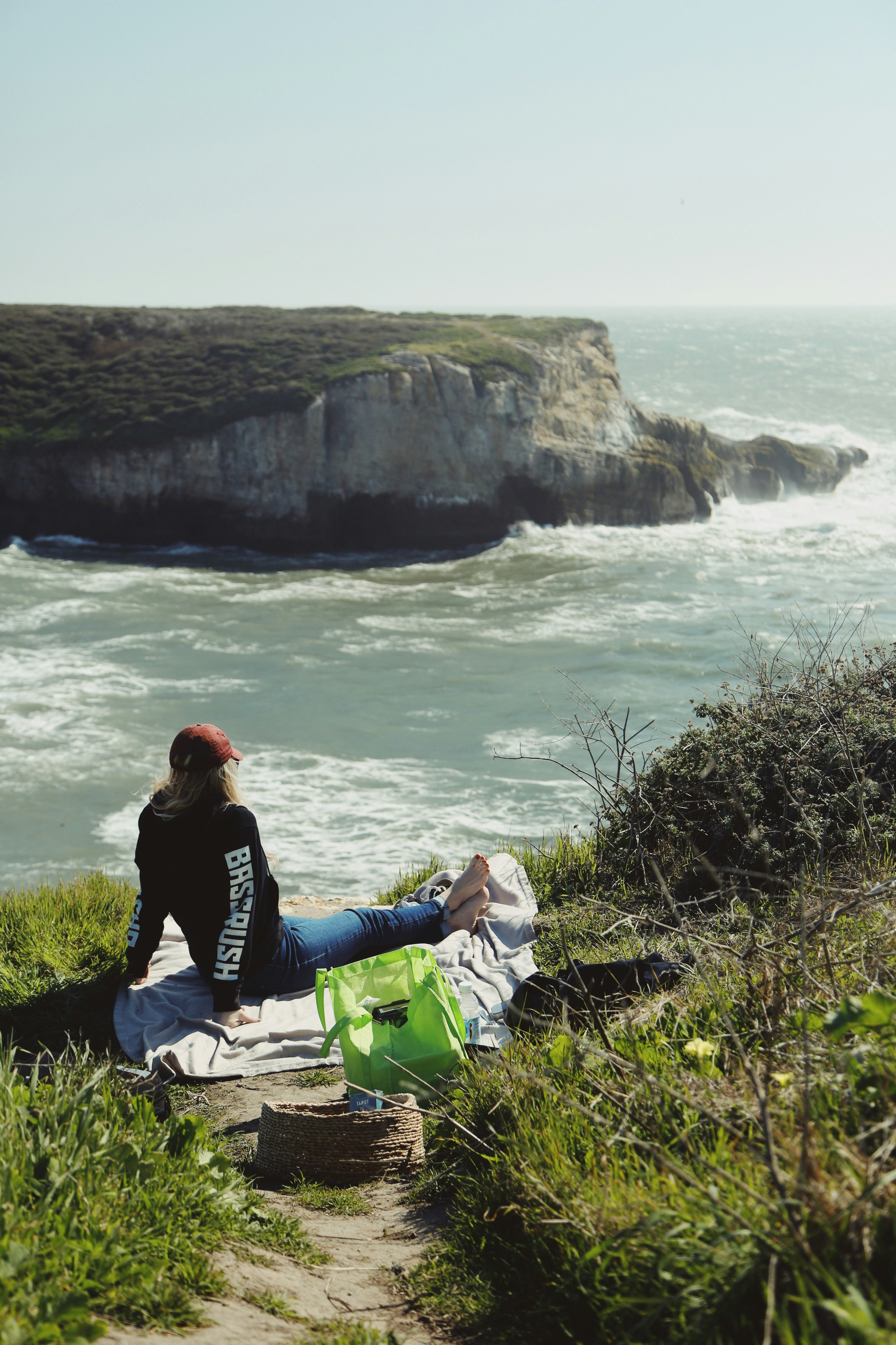 man in black jacket sitting on rock near body of water during daytime