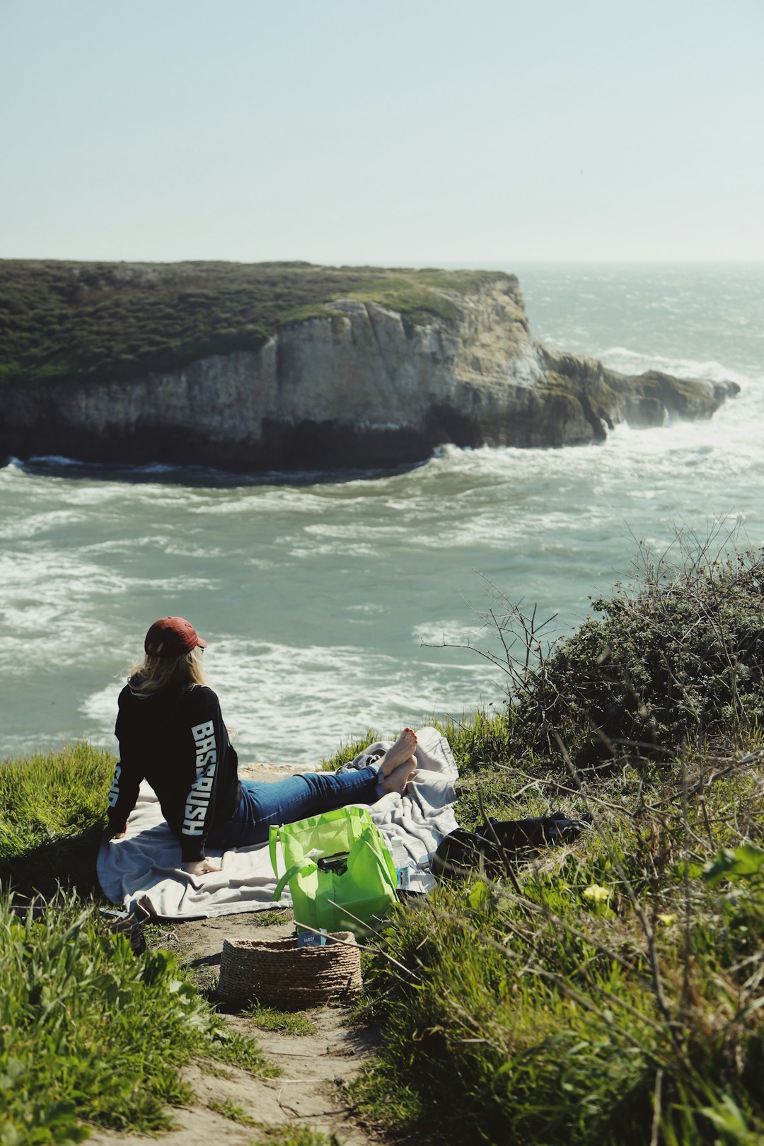 man in black jacket sitting on rock near body of water during daytime