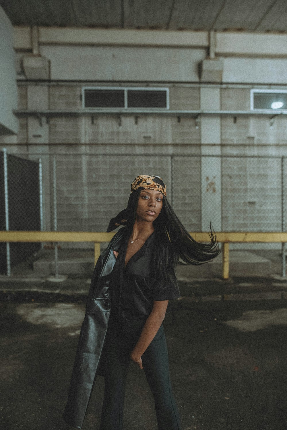 woman in black leather jacket standing on road during daytime