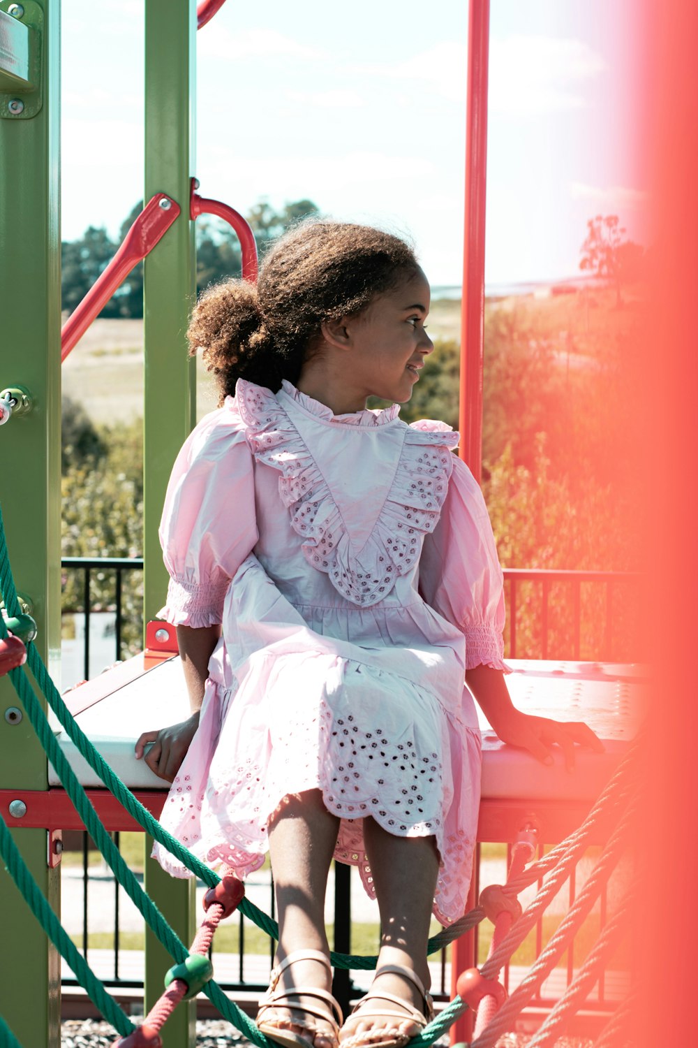 girl in pink and white dress sitting on red wooden chair