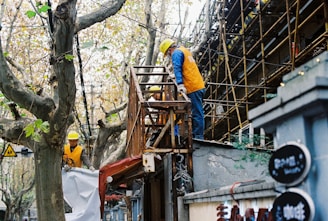 man in yellow hard hat and white long sleeve shirt climbing on ladder