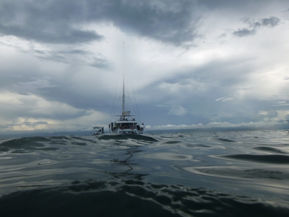 a boat floating on top of a body of water under a cloudy sky