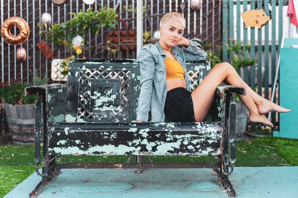 woman in blue denim vest sitting on black metal bench