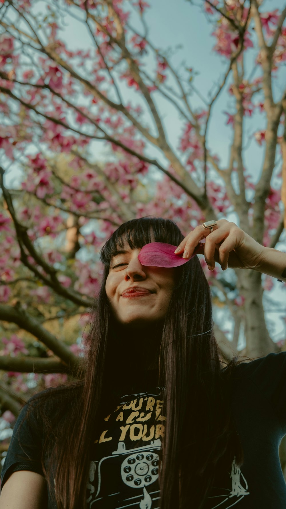 woman in black shirt holding pink heart ornament