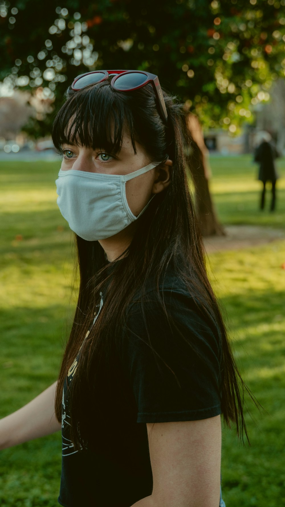 donna in camicia nera che indossa una maschera facciale bianca