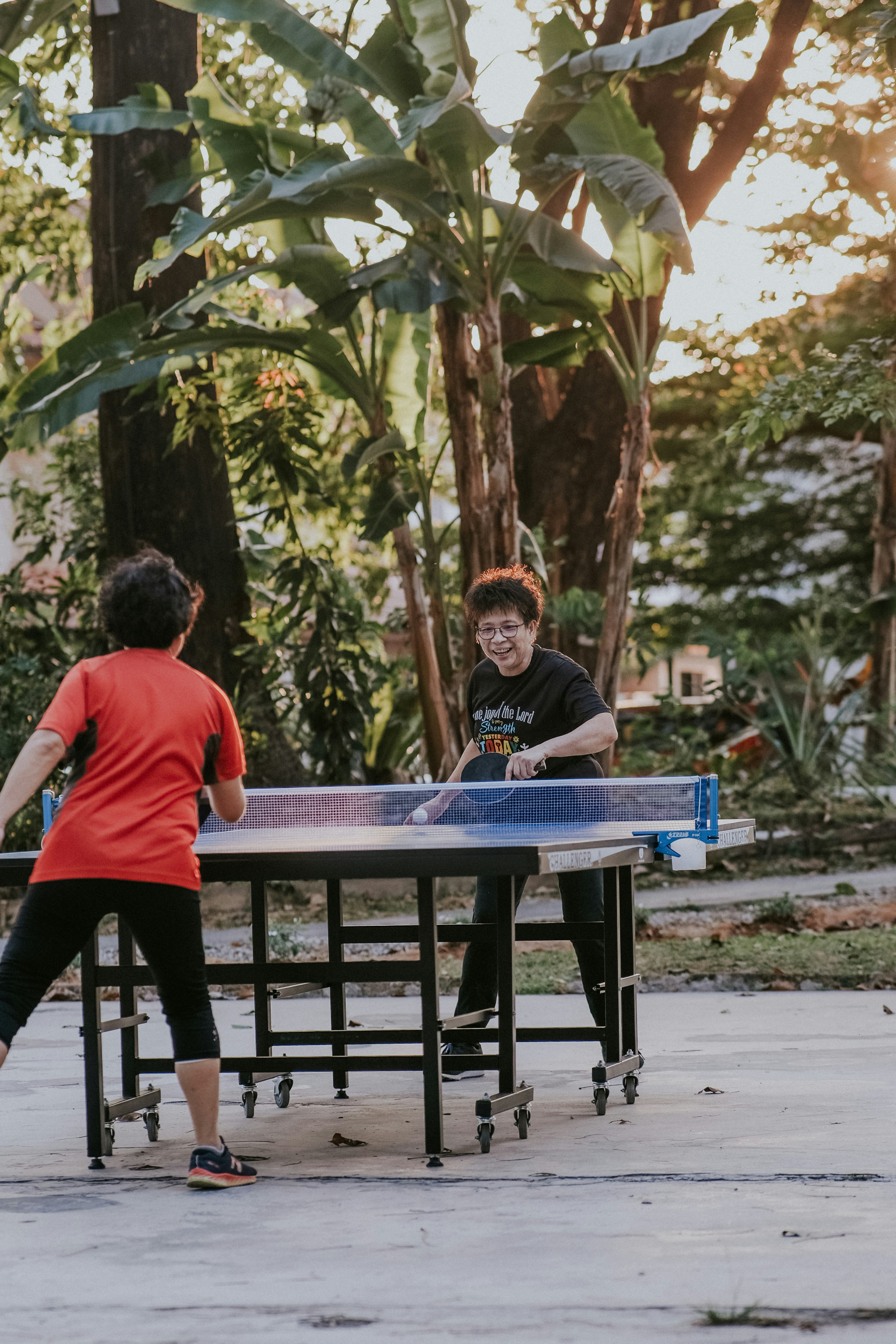 Chinese elderly woman playing table tennis/ping pong in a park in Malaysia. 