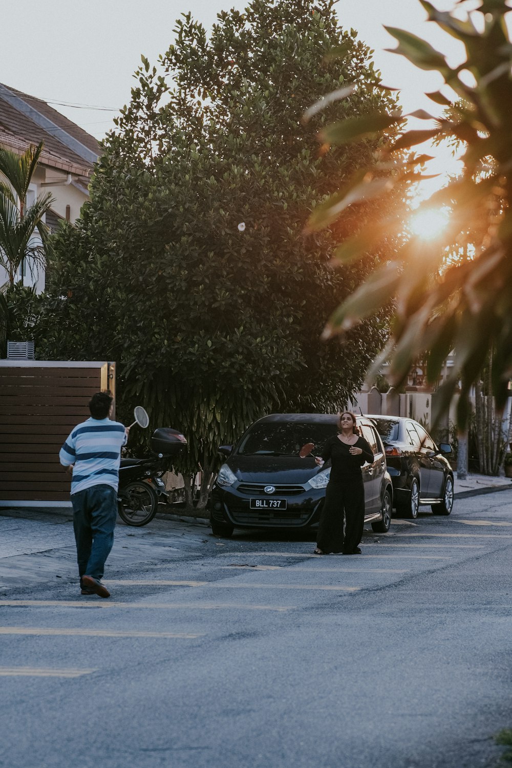 Homme en veste noire et jean bleu debout à côté d’une voiture noire pendant la journée