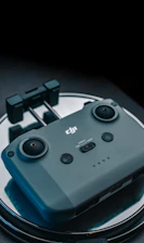 Close-up of drone controls with black and orange accents, resting on a sleek black surface.