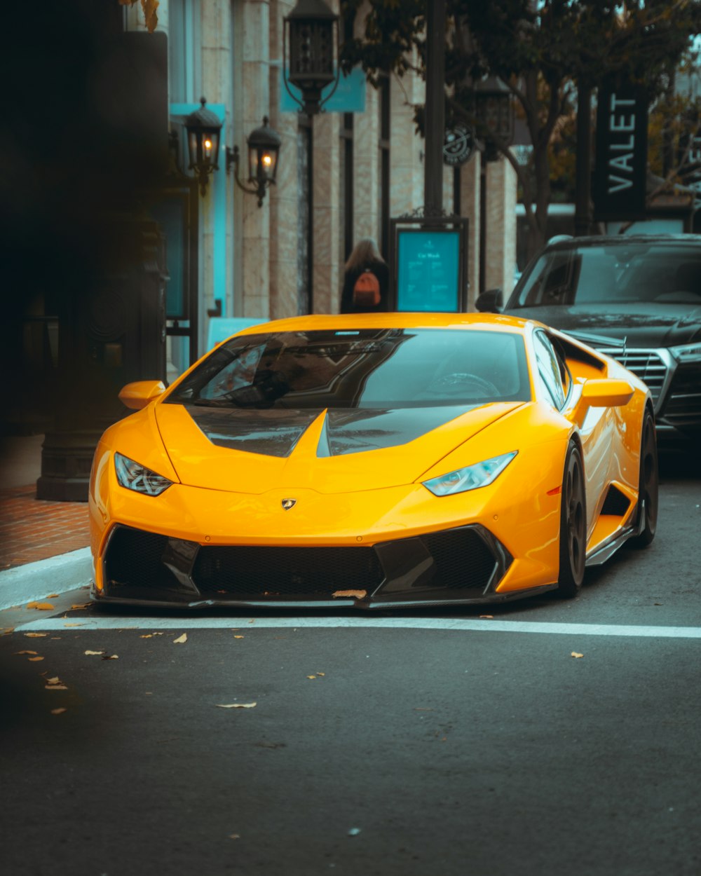 orange lamborghini aventador parked on sidewalk during daytime