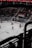 A hockey game is taking place in an indoor arena with players dressed in red and white uniforms on the ice. The stands have a sparse crowd watching the game, and banners with text and year numbers are displayed above the audience. The environment is dimly lit, giving the impression of a professional sports event.